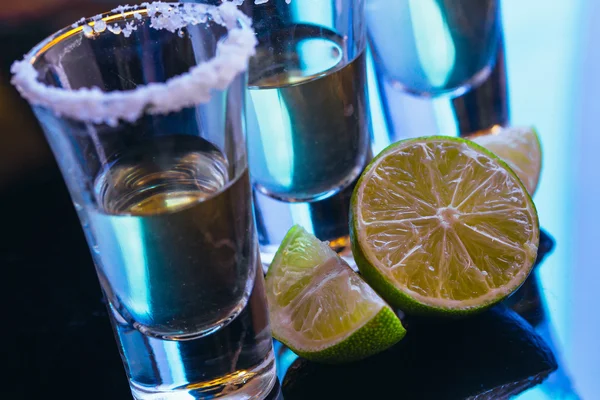 Stack of tequila with salt close up on blurred background — Stock Photo, Image