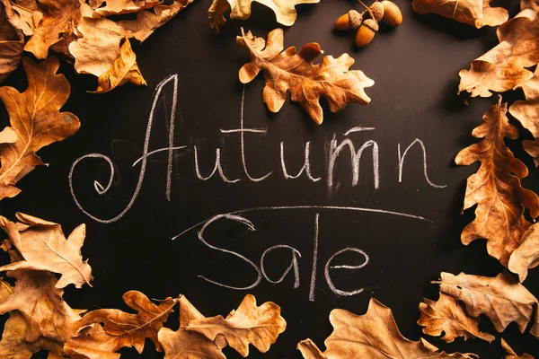 Yellow leaves and the words autumn sale on a blackboard vintage style — Stock Photo, Image