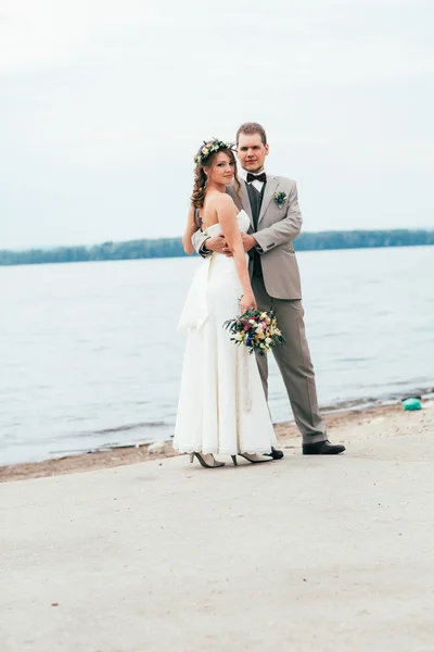 Jeune marié et mariée debout étreinte sur le fond de la rivière — Photo