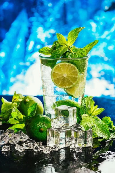 Vidro de mojito com limão e cubo de gelo de hortelã close-up palha vermelha no fundo azul — Fotografia de Stock