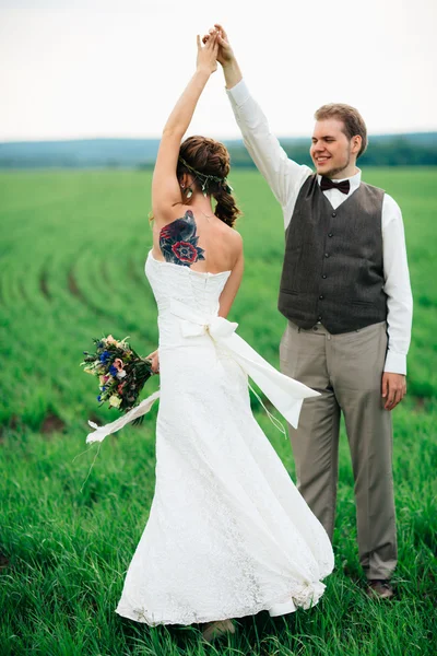 La mariée et le marié avec un bouquet sur le champ vert — Photo