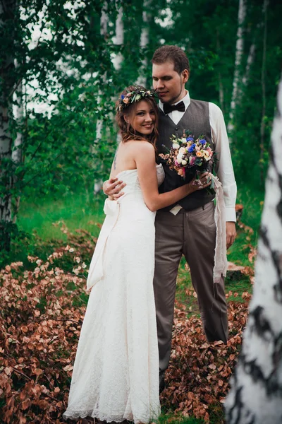 Bruid en bruidegom knuffelen op de achtergrond van bladeren bos — Stockfoto