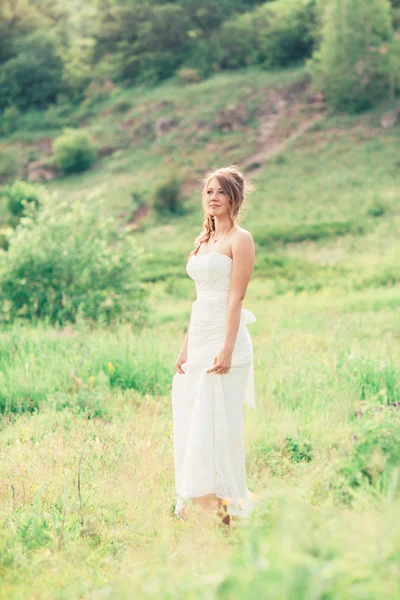 Bride stands on a background of grass and mountains — Stock Photo, Image