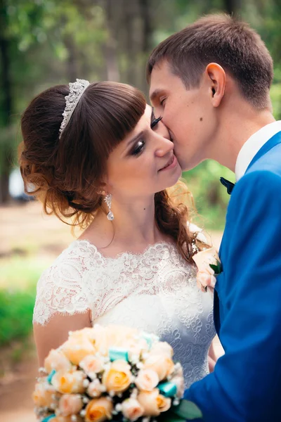 Jeune mariée et marié baisers sur le fond de la forêt la route — Photo