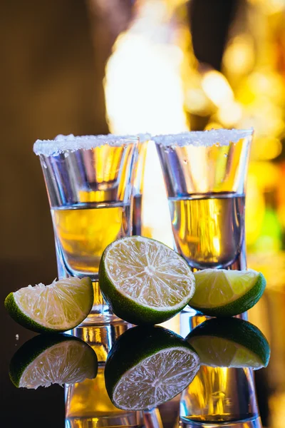 Pilha de tequila com sal de perto sobre fundo borrado — Fotografia de Stock