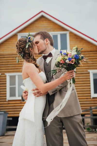 Noiva e noivo beijando abraços no fundo da casa — Fotografia de Stock