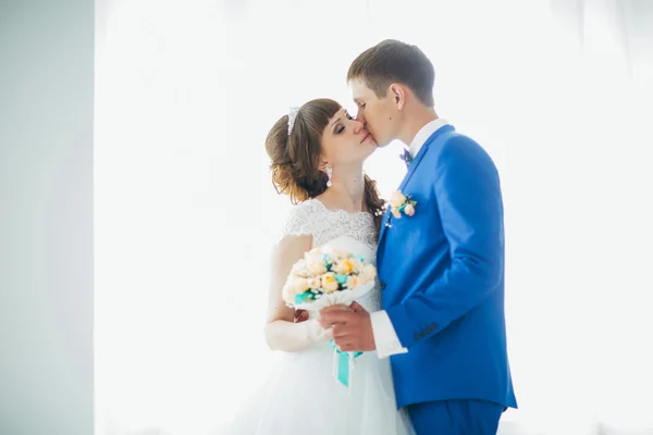 Novia y novio en estudio luz pie beso sobre un fondo blanco — Foto de Stock