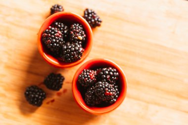 Böğürtlen ahşap plakalar üzerinde arka plan bulanık bir fincan