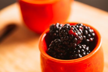 Böğürtlen ahşap plakalar üzerinde arka plan bulanık bir fincan