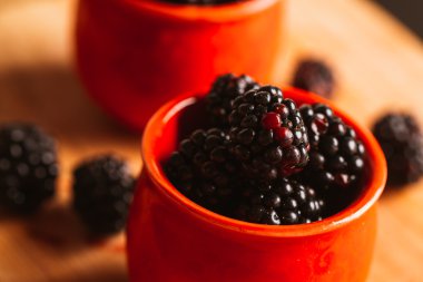 Böğürtlen ahşap plakalar üzerinde arka plan bulanık bir fincan