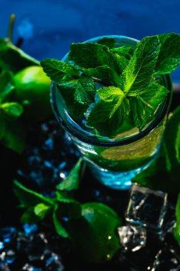 mojito limon ve nane buz küp yakın çekim kırmızı saman ile mavi arka plan üzerinde bardak