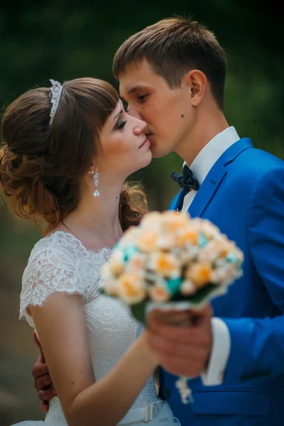 Young bride and groom kissing on the background of the forest — Stock Photo, Image