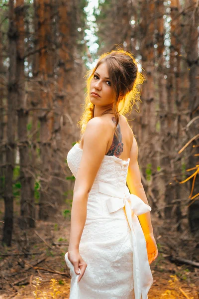 Bride with a tattoo on  background of leaves and forest backlight — Stock Photo, Image