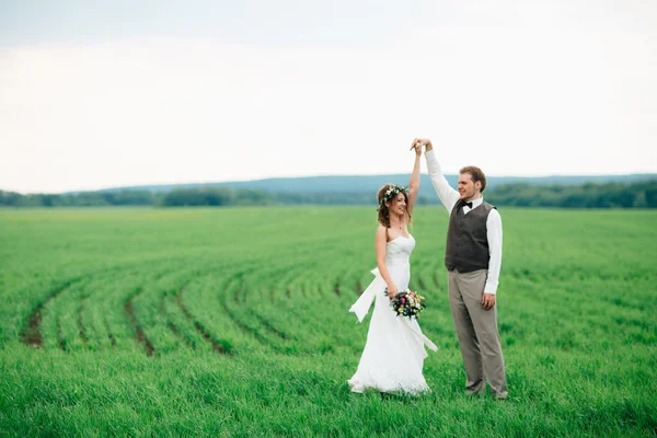 A menyasszony és a vőlegény egy-egy csokor zöld mezőn — Stock Fotó