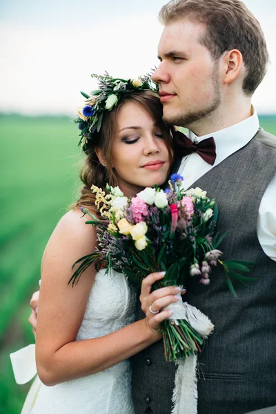 Porträtt av bruden och brudgummen med en bukett på det gröna fältet — Stockfoto