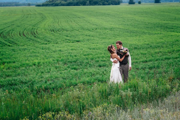 La mariée et le marié avec un bouquet sur le champ vert — Photo
