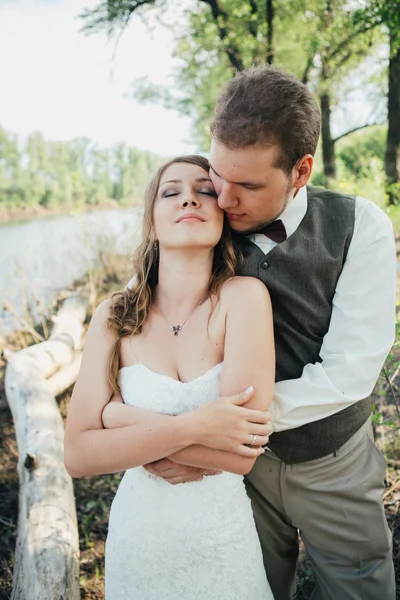 Mariée et marié debout bras dans les lacs d'herbe de fond — Photo