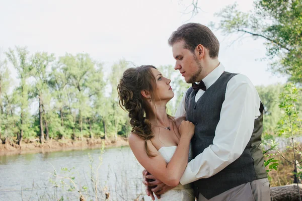 Mariée et marié debout bras dans les lacs d'herbe de fond — Photo