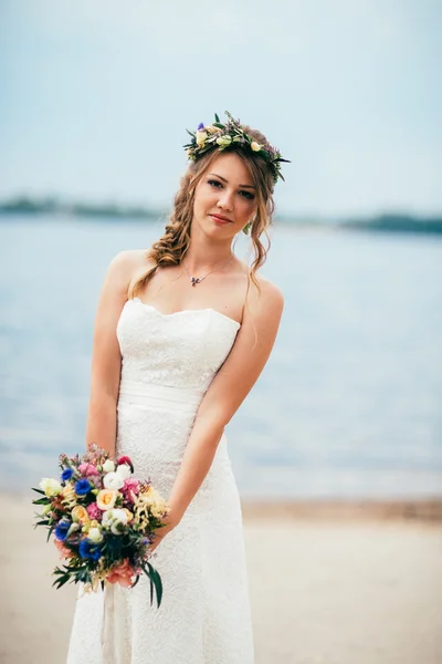 Joven novia con un ramo de flores de pie en el fondo del río —  Fotos de Stock
