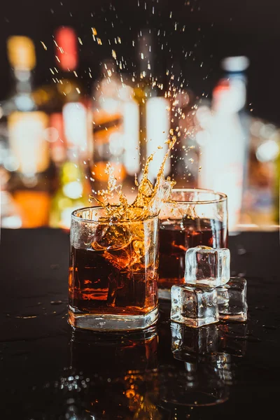 two glasses of whiskey on a blurred background bar