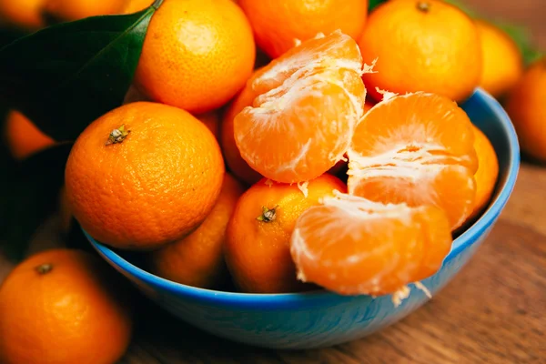 Багато свіжих мандаринських апельсинів у синій мисці, що стоять на дерев'яному столі — стокове фото