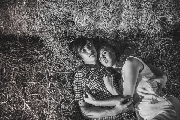 Jongen en gil lyingyoung jongen en gyrl liggen in het hooi. Buiten zomer portret van mooie paar. in het hooi. Buiten zomer portret van mooie paar. — Stockfoto