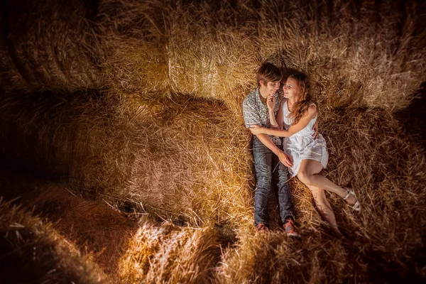 Chico joven y gil mintiendo Chico joven y girando acostado en el heno. Retrato de verano al aire libre de hermosa pareja. en heno. Retrato de verano al aire libre de hermosa pareja . — Foto de Stock