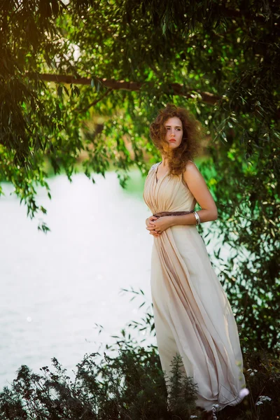 Vrouwelijke model in lang beige jurk dynamische poseren in het strand. zwaaien weefsel. fladderende lange rok — Stockfoto