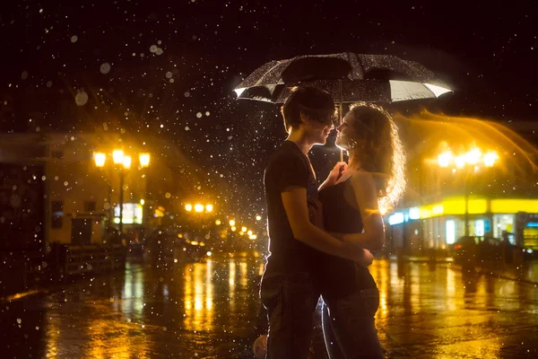 La chica con el chico besándose bajo una lluvia torrencial —  Fotos de Stock