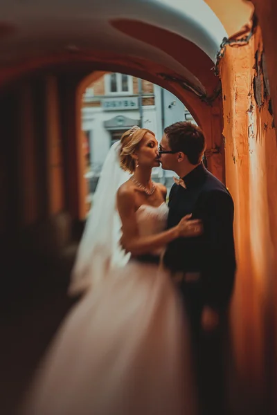 Detailní portrét nevěsta a ženich líbat v starověké tunelu z cihel — Stock fotografie