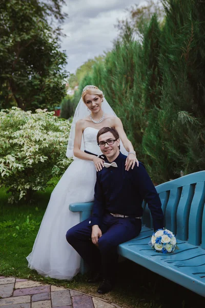 Casamento tiro de noiva e noivo sentar no banco no parque — Fotografia de Stock