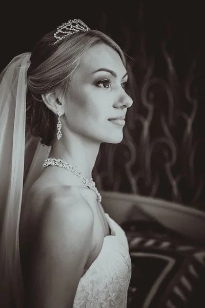 Bruden i en vacker klänning nära fönstret — Stockfoto