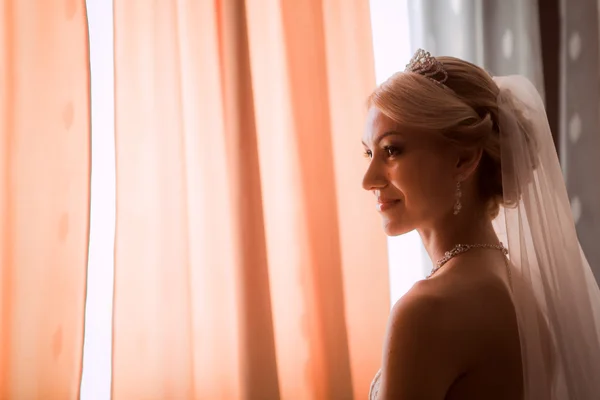 Braut in einem schönen Kleid am Fenster — Stockfoto