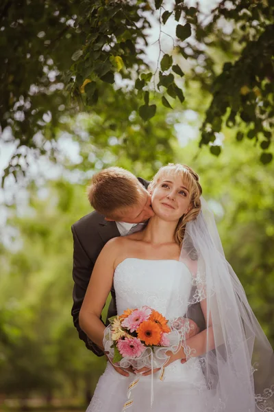 Mariée et marié dans un parc kissing.couple jeunes mariés mariée et marié à un mariage dans la forêt verte nature embrassent photo portrait.Wedding couple amour — Photo