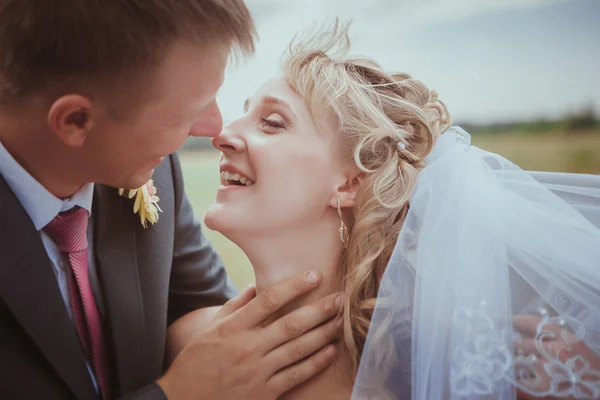 Beautiful bride and groom standing in grass and kissing. Wedding couple fashion shoot. — Stock Photo, Image