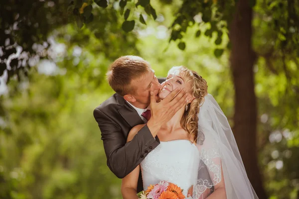 Noiva e noivo em um parque beijando.casal recém-casados noiva e noivo em um casamento na natureza floresta verde estão beijando foto retrato.Casamento Casal Amor — Fotografia de Stock