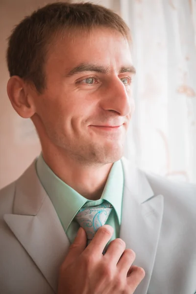 年轻的新郎在为婚礼做准备时系领带的结的肖像 — 图库照片