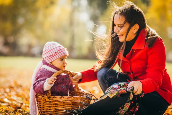 Kid en moeder zitten met appels mandje buitenshuis in herfst park — Stockfoto