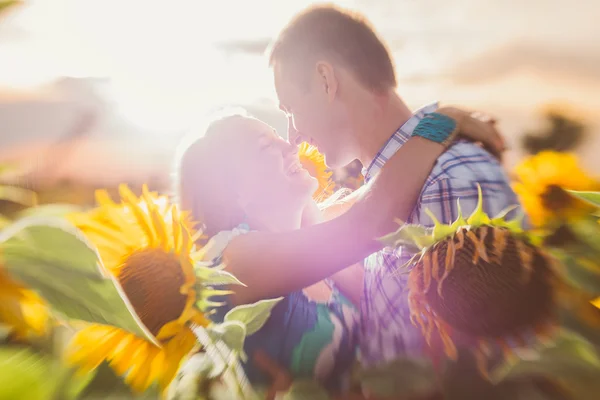 Vackra par att ha roligt i solrosor fält — Stockfoto