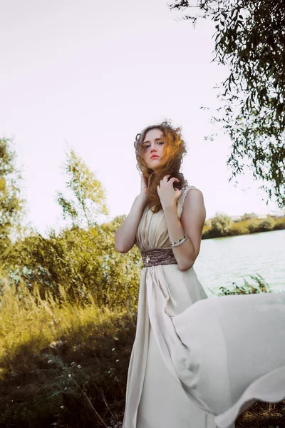 Menina bonita em vestido branco em uma costa do lago — Fotografia de Stock