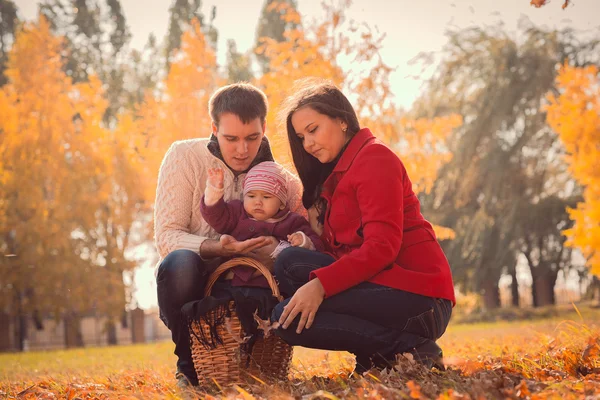 Glückliche junge Familie verbringt Zeit im herbstlichen Park — Stockfoto