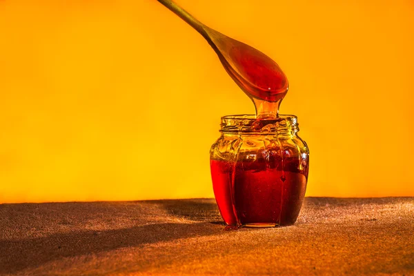 Honey jar with spoon and flowing honey,  canvas background — Stock Photo, Image