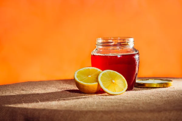 Botol madu, lemon dan madu mengalir, latar belakang kanvas — Stok Foto