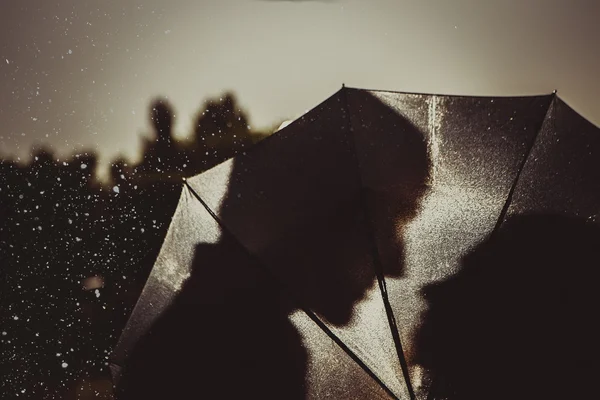 Amor na chuva / Silhueta de casal beijando sob guarda-chuva — Fotografia de Stock