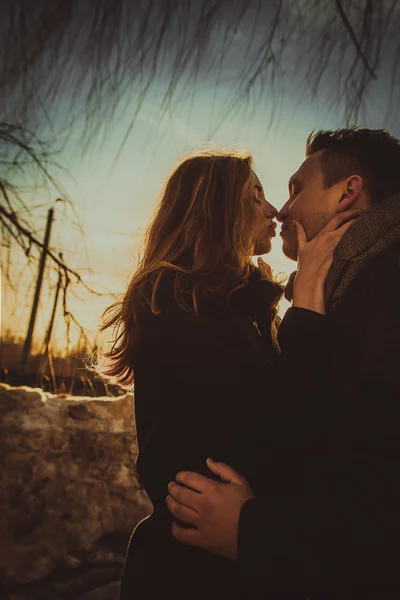 Paar küsst sich im Park bei Sonnenuntergang. Foto im mehrfarbigen Bildstil. — Stockfoto