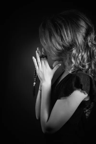 Драматический черно-белый портрет женщины, молящейся или думающей, выходящей на черном фоне — стоковое фото