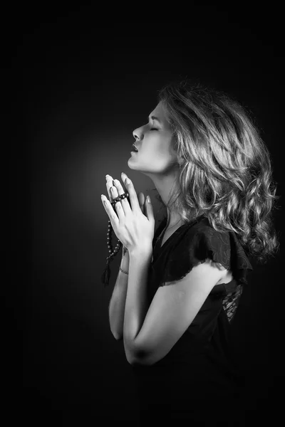 Potret hitam dan putih dari seorang wanita berdoa atau berpikir muncul dari latar belakang hitam — Stok Foto