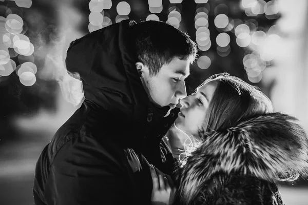 Zimní pár proti barevné svítící tečky na černém pozadí — Stock fotografie