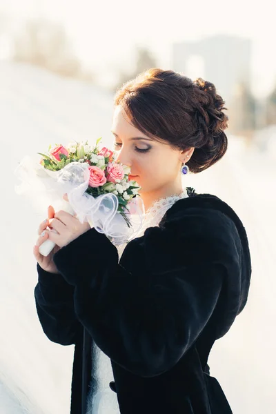 Bella sposa con bouquet posa all'aperto nella neve — Foto Stock