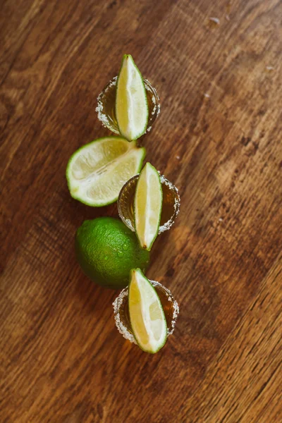 Tequila, limão e sal sobre mesa de madeira — Fotografia de Stock